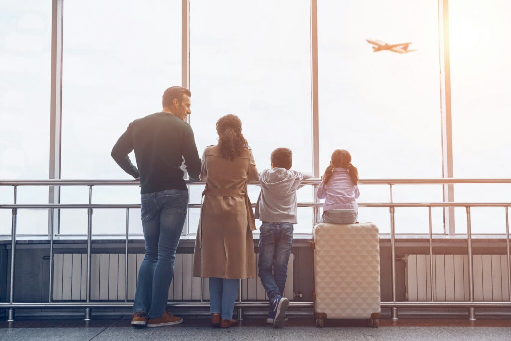 Full length of family with two little kids looking at the flying airplane